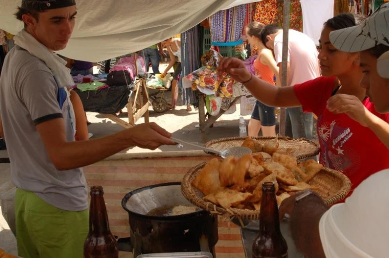 a man is serving food from a pail outside