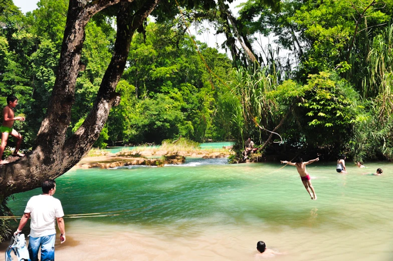 people jumping into the water and playing at a lake