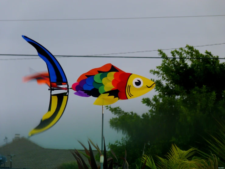 a colorful kite flying with a fish made out of a material