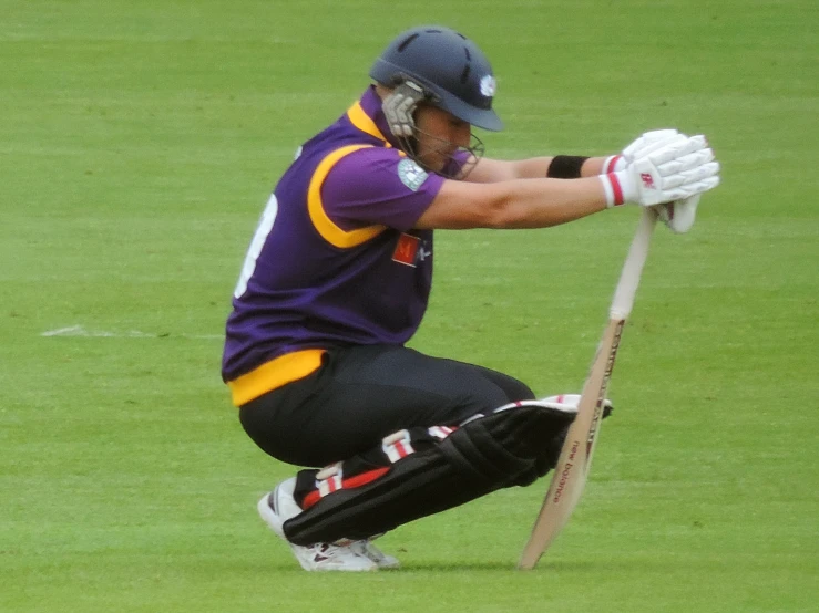 a male in a uniform playing softball, holding his bat