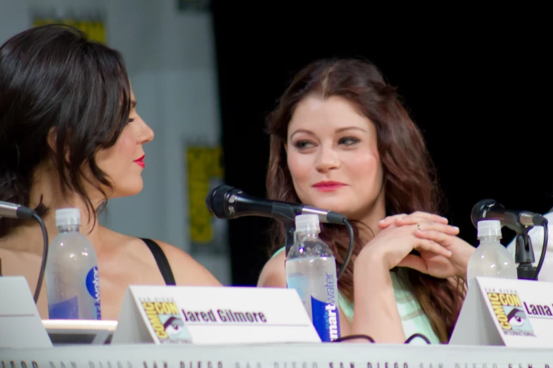 two women sitting at a table in front of microphones