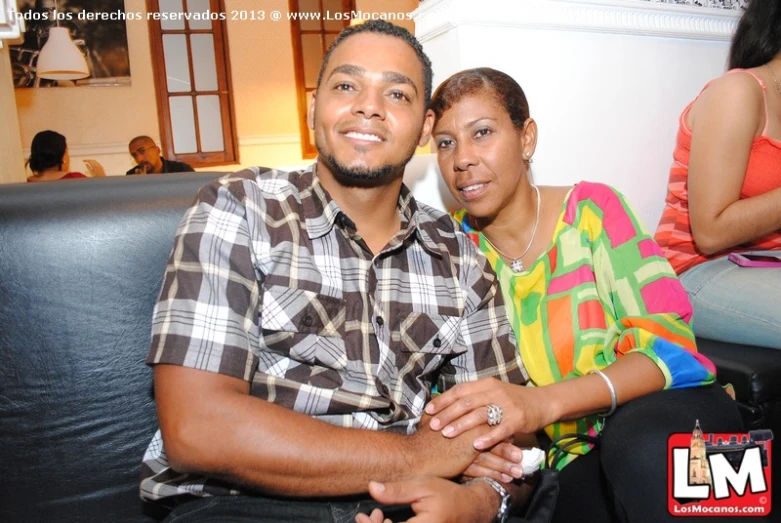 a man and woman pose on a leather couch