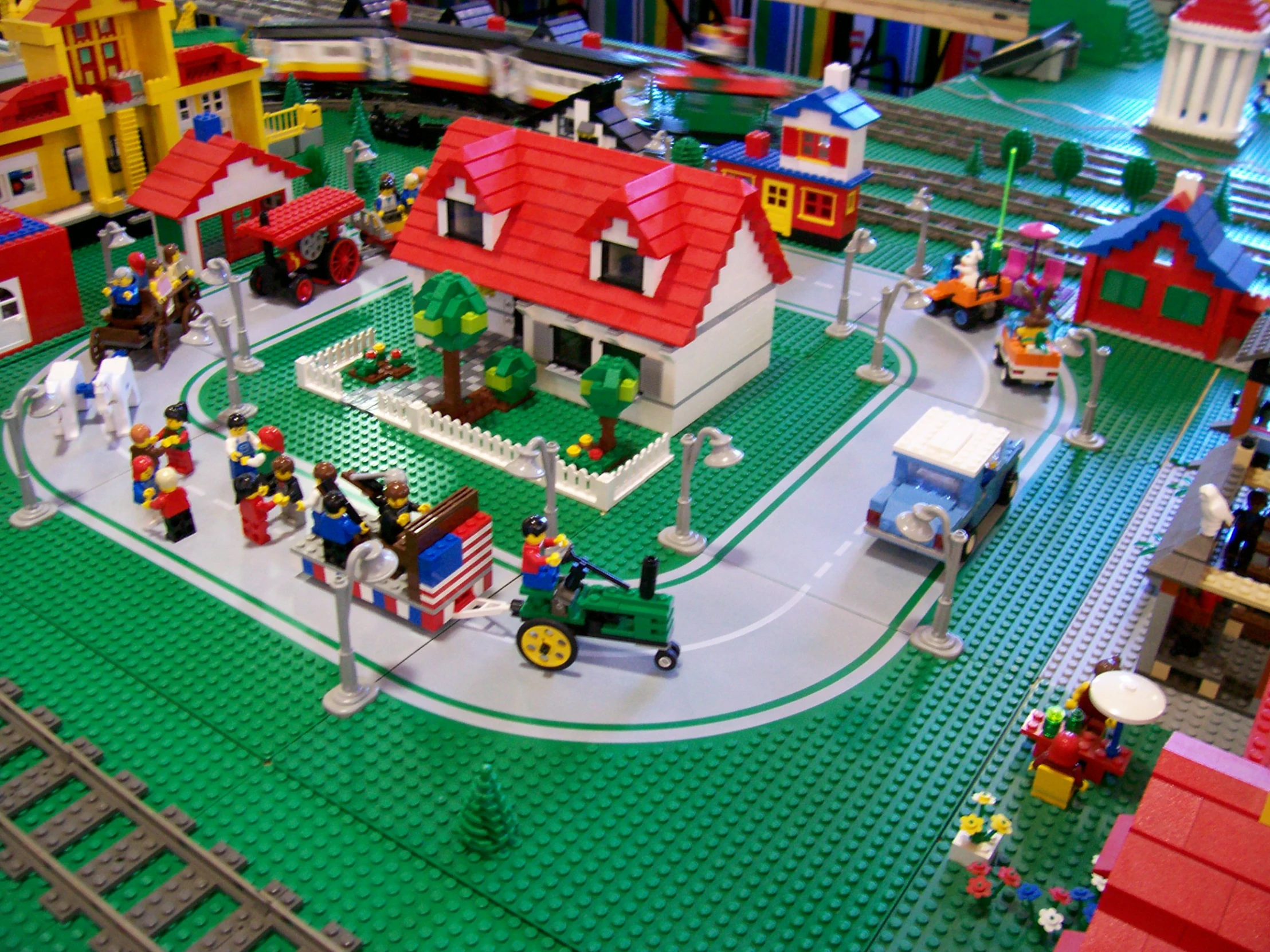 a small lego town with a train, a car and a motorcycle