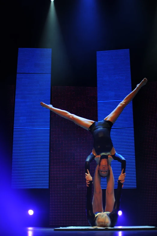 two acrobatic performers performing on top of one another