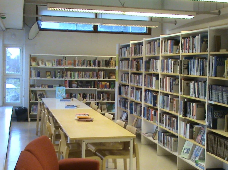 a room full of books and table that has chairs