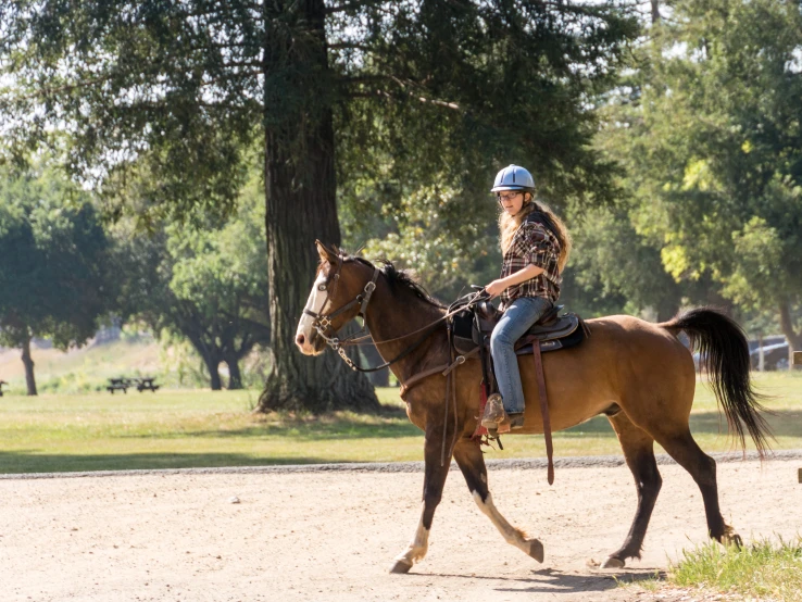 the person is riding her horse outside in the country