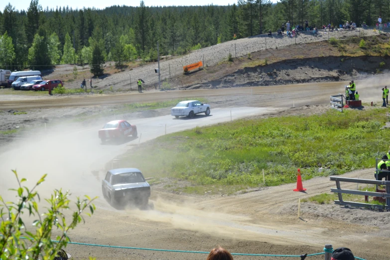 several cars driving in the dirt and around cones