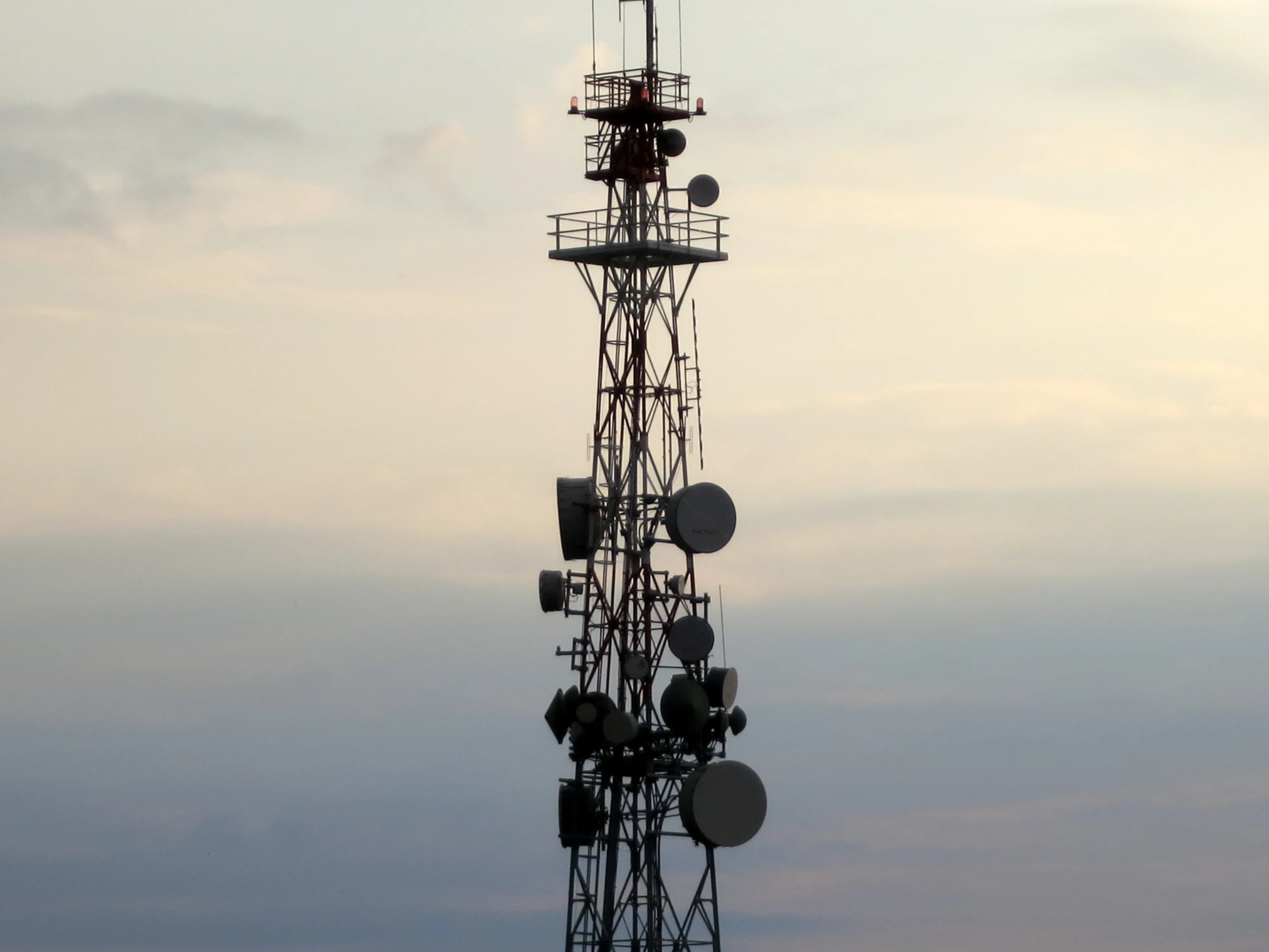 a large tower has several radio antennas on top of it