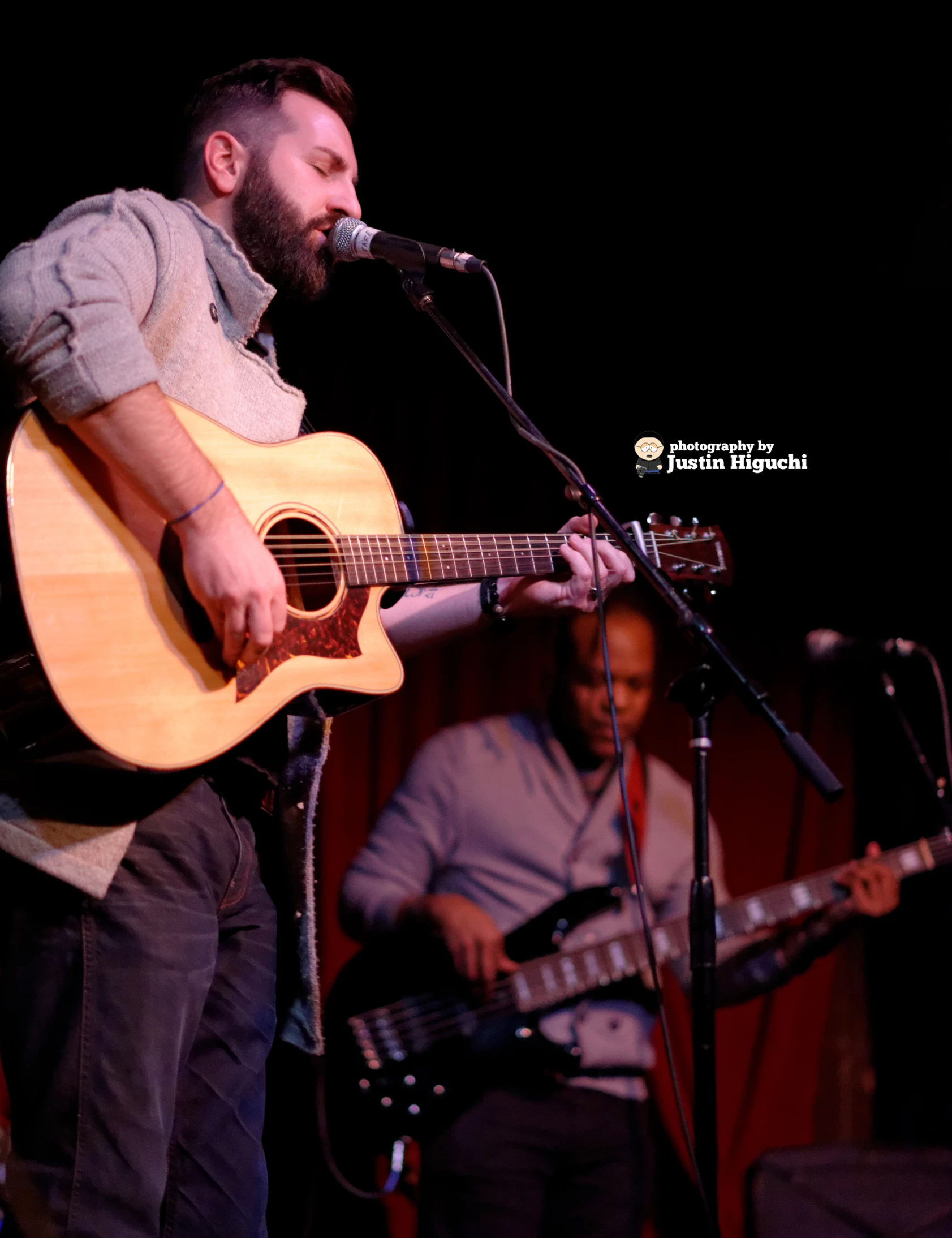 a man is playing guitar and singing into a microphone