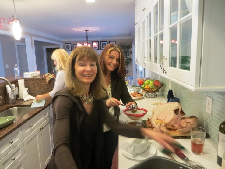 three women standing in a kitchen preparing food