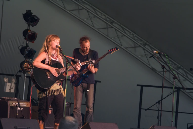 two people playing guitar on stage with musical instruments