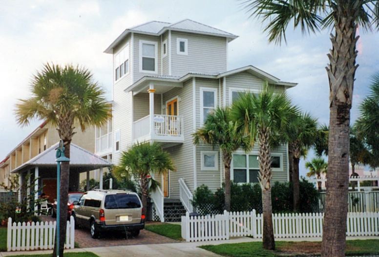 a white and gray house with a car in front of it