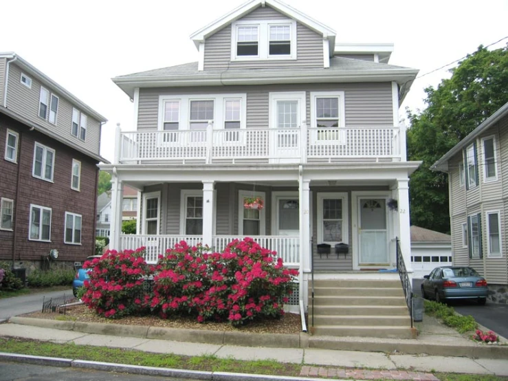 the front view of a two story house with flowering shrubs on the front lawn