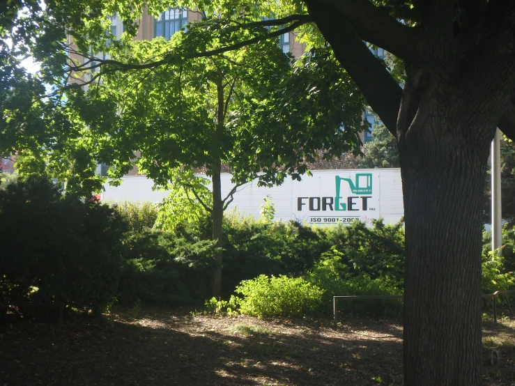 some trees grass bushes and signs and a building