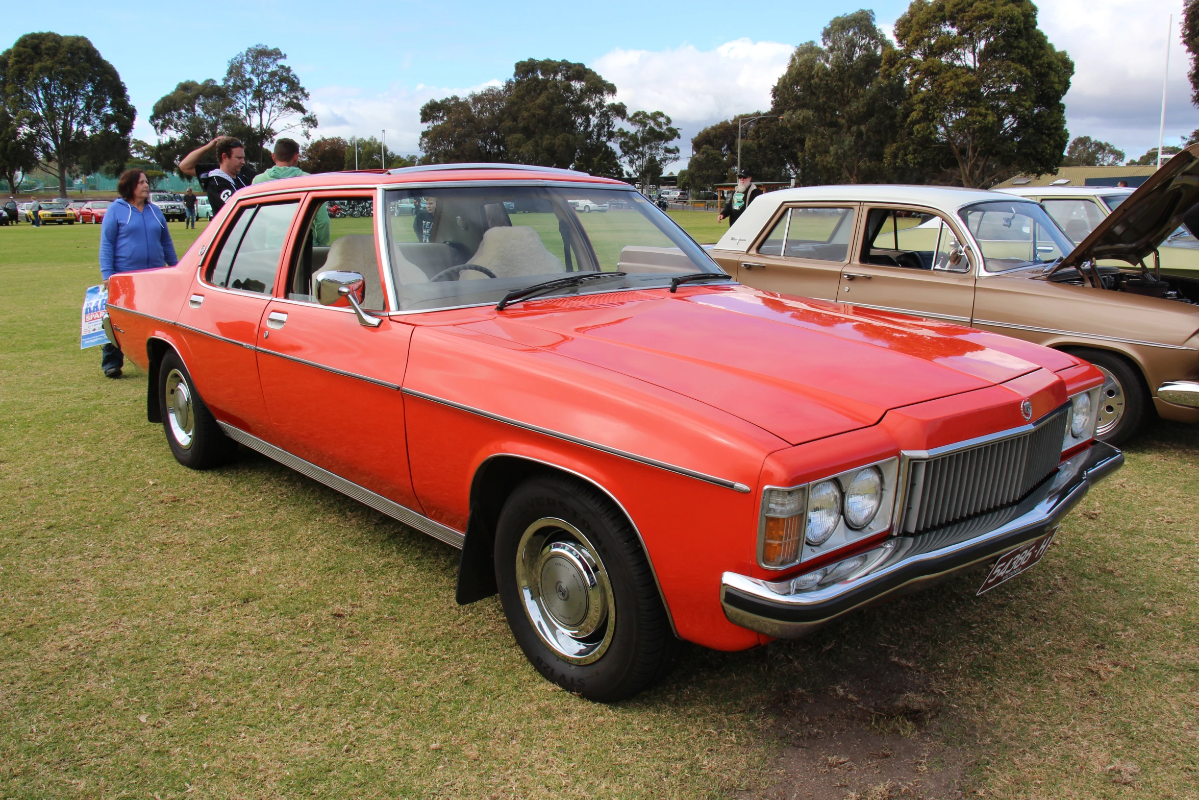 a bright red car sitting in the middle of some grass