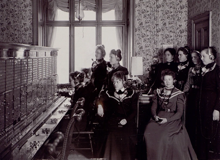 several ladies in costumes stand next to each other by an old machine