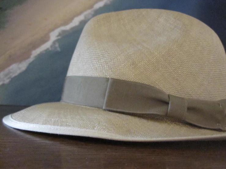 a light colored hat with a gray bow is sitting on a table