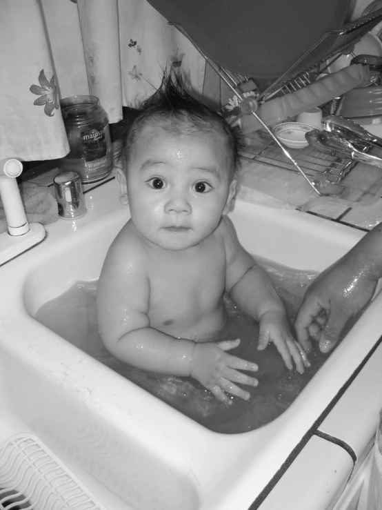 a baby in a sink that is getting his bath