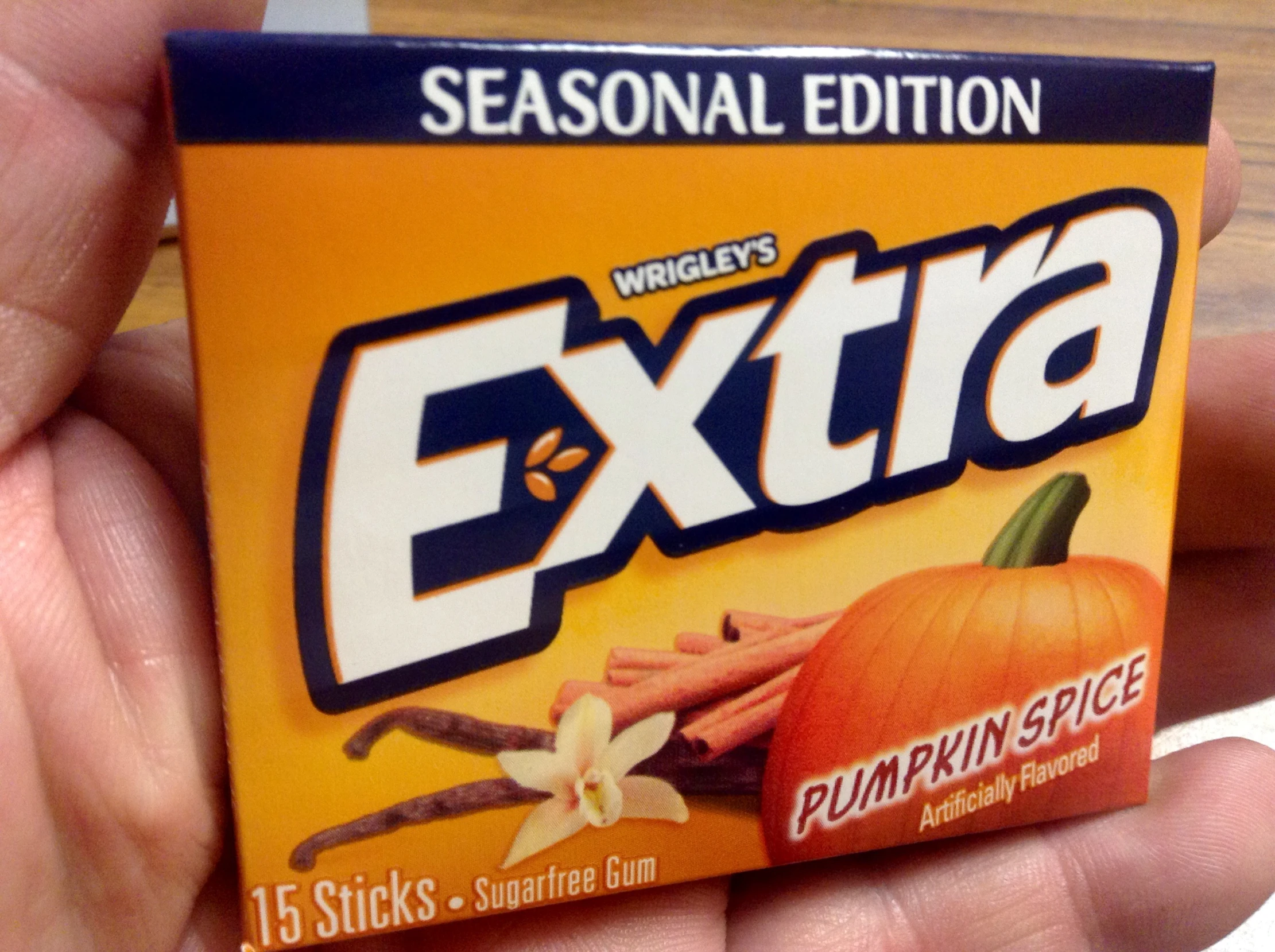 a person holding an orange package of extra pumpkin spice