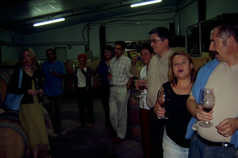 people standing in the middle of a line with wine glasses