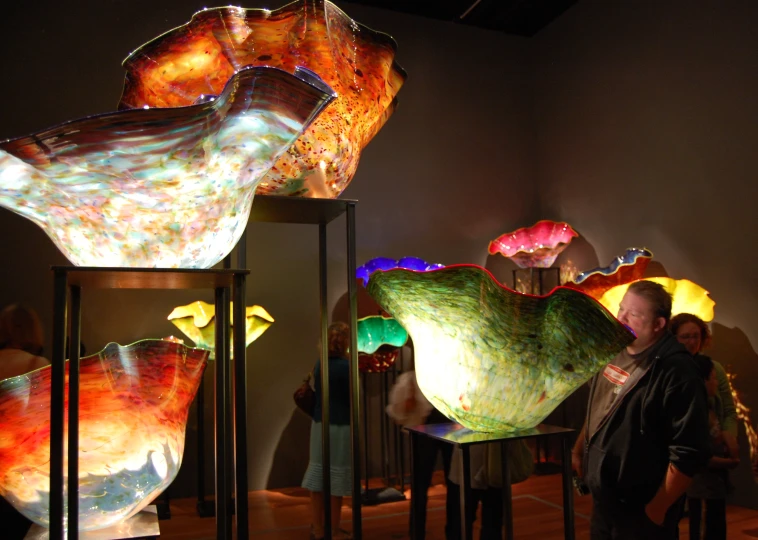 many glass bowls are displayed in an art gallery