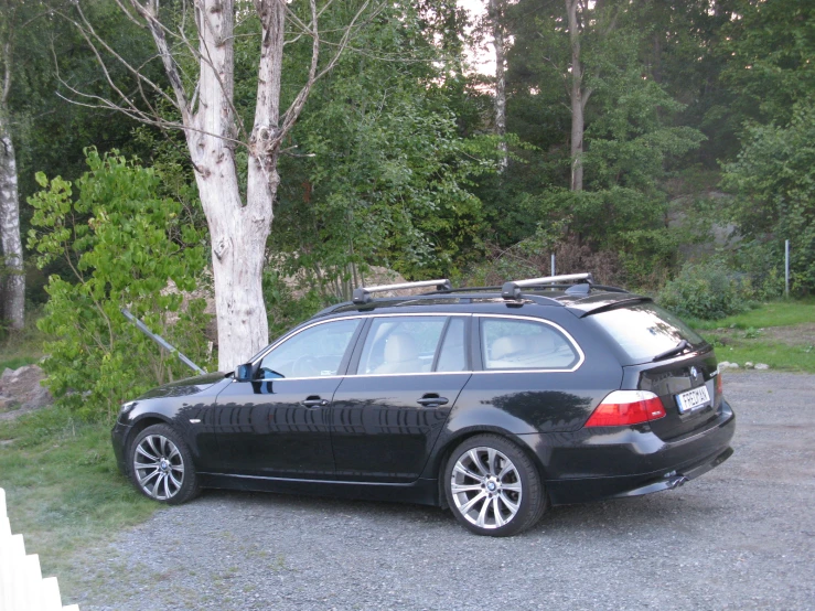 the back of a vehicle parked in the driveway with trees and shrubs in the background