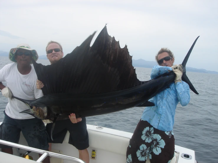 two people holding a large animal on the back of a boat