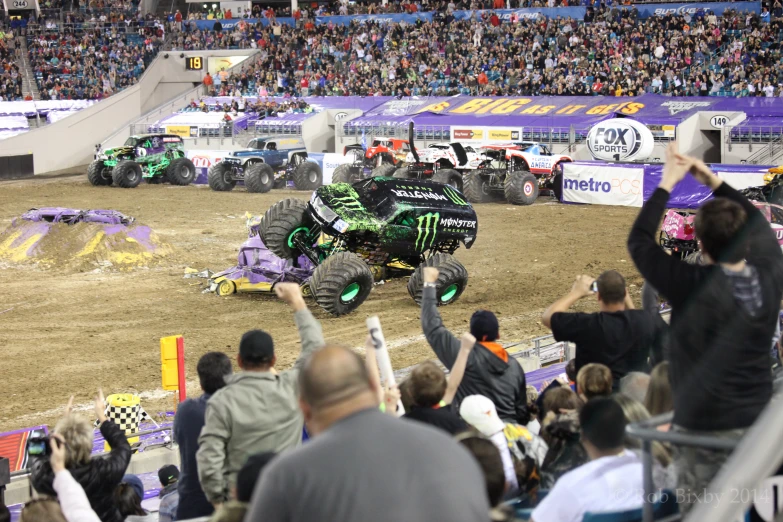 monster trucks at an auto racing competition, with a crowd