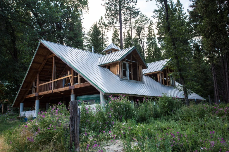 a log cabin with metal roof and flowers on the ground