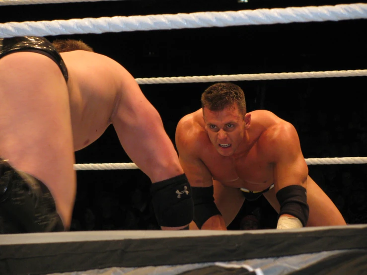 two men wrestling in a ring one is bending down