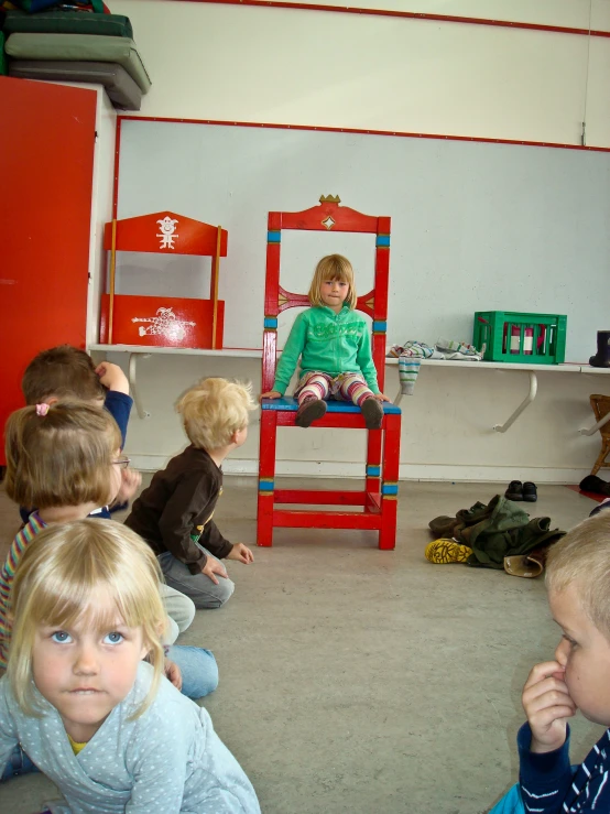 several children are sitting around on the floor in chairs and talking