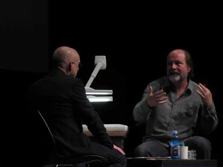 two men sitting in a chair, talking