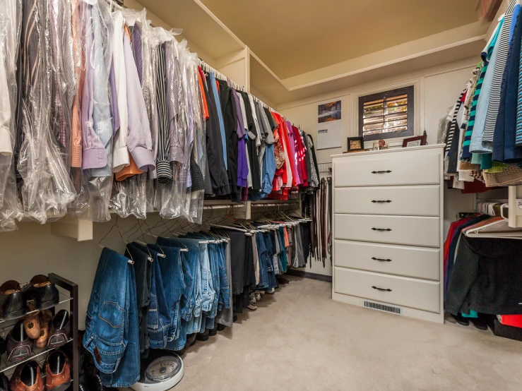 there is a closet with various jeans on racks