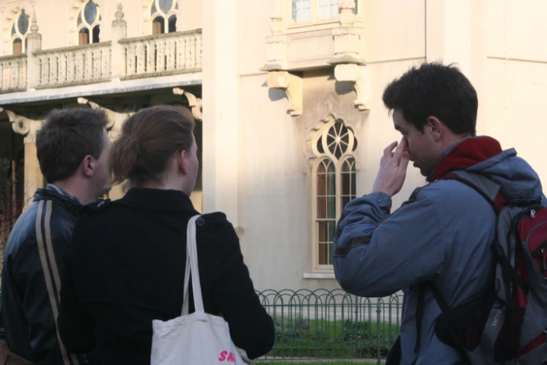 three friends standing outside in front of the building