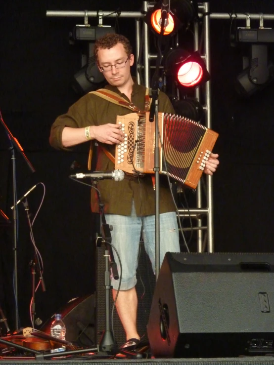 a man with glasses and a accord player on stage