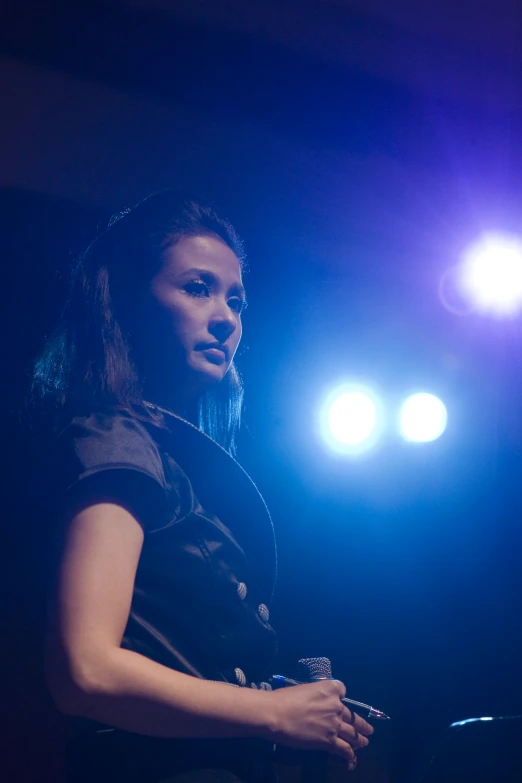 a woman is standing up on a stage with spotlights