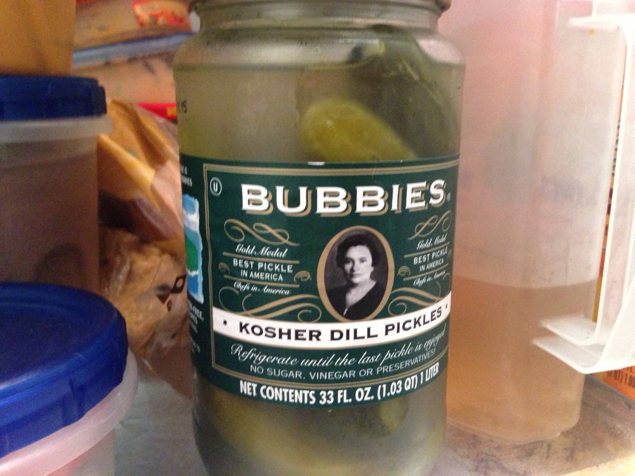 there is a pickle in a glass bottle near other containers