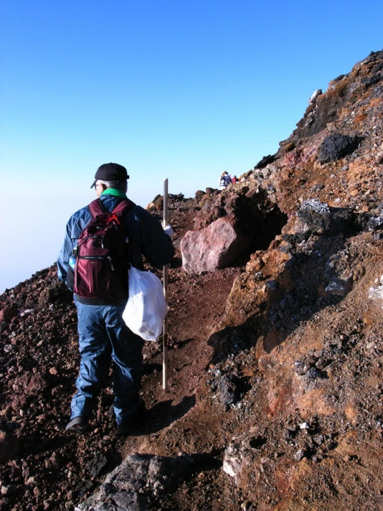 a man with a backpack hiking uphill carrying soing