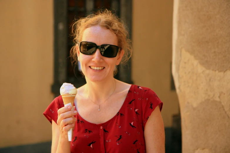woman smiling holding an ice cream cone with a red dress