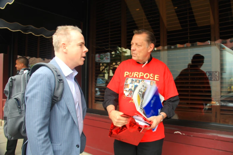 the two men are talking outside of the store