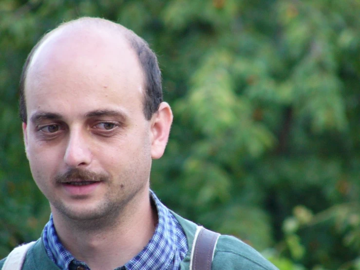 a man with dark glasses and a moustache is looking into the camera