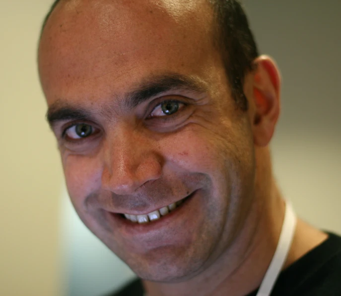 a man smiling at the camera, with a collared shirt on