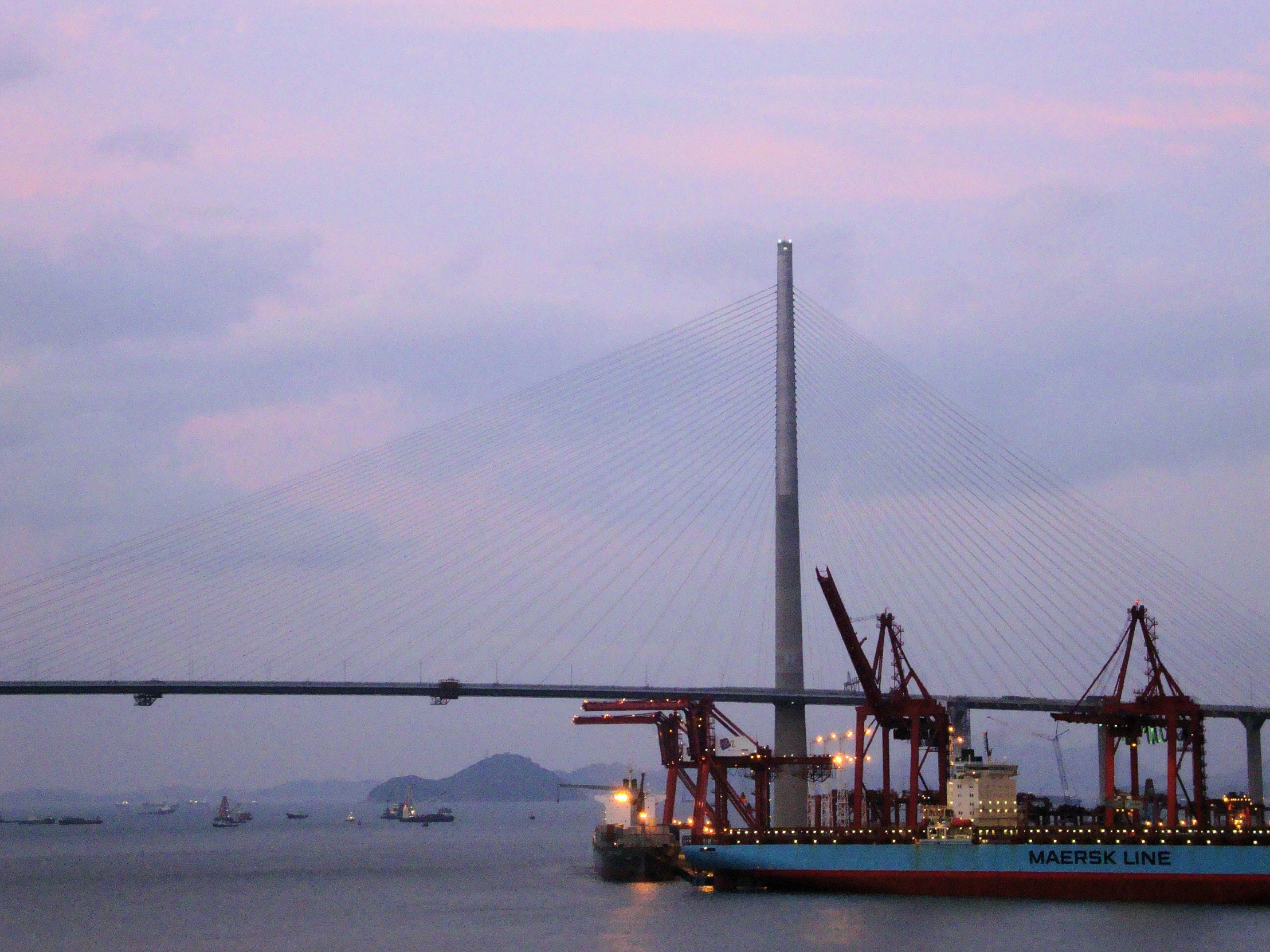 two large boats sitting out on the water near a bridge