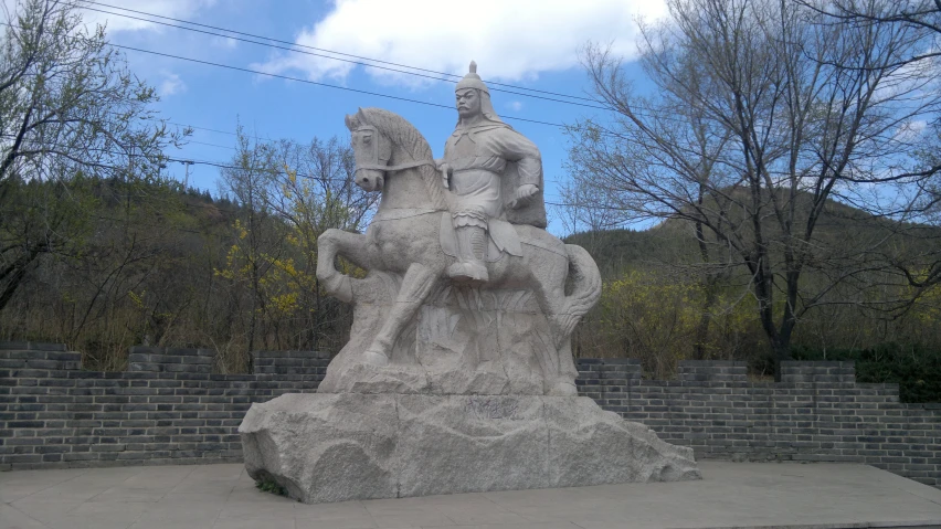 statue of man on horse sitting in front of wall with mountains