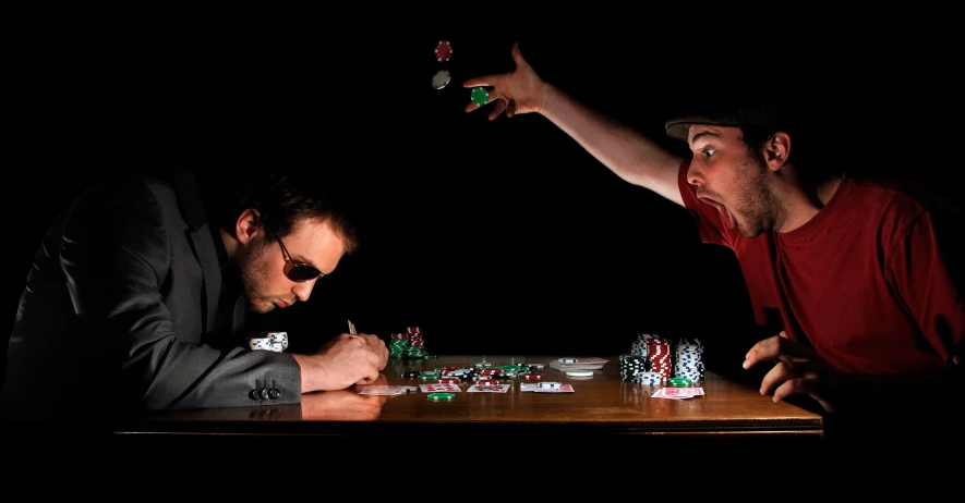 two men sitting at a table playing poker