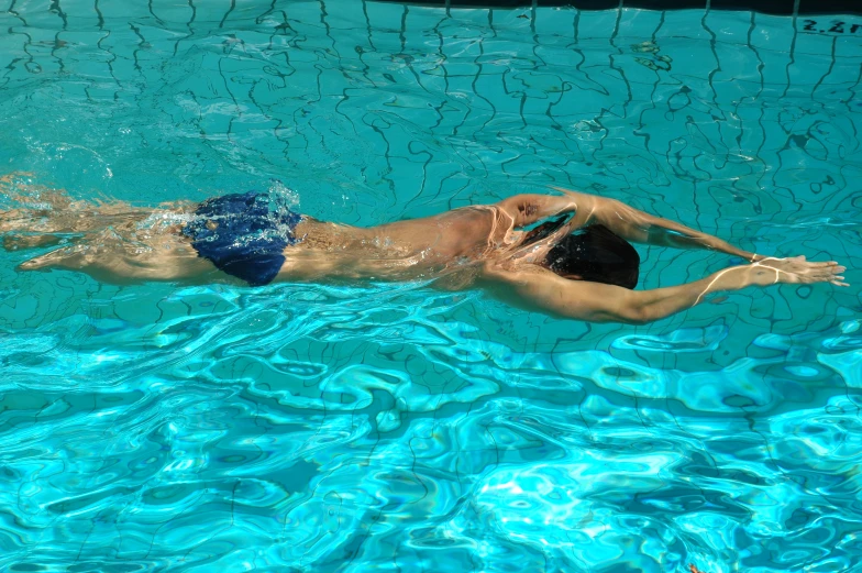 a woman wearing a hat and swimming in the pool