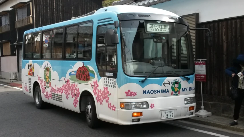 a city bus with pictures painted on the side and people standing near it