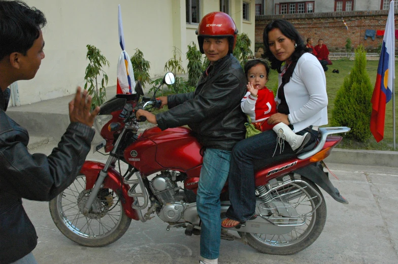 a man, woman, and child are sitting on the back of a motorcycle