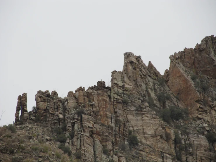 a very tall rocky cliff on a cloudy day