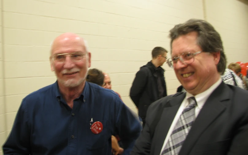 two older gentlemen wearing ties and smiling at an event